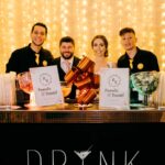 Bartenders tirando foto com os noivos atrás do balcão na festa de casamento