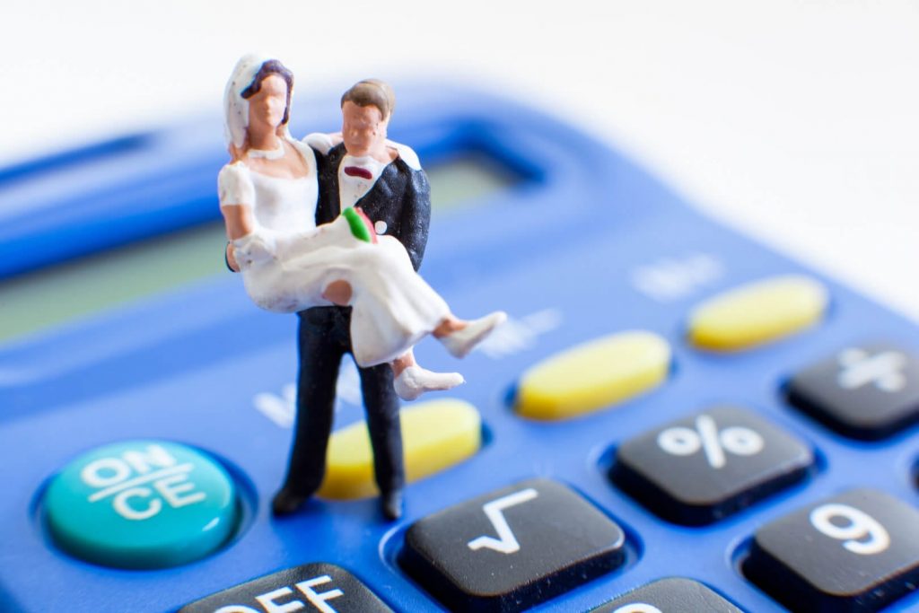 miniatura de noivos em cima da calculadora orçando serviço de barman