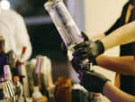 Bartender usando dosador para dosar a quantidade de bebida, representando a mão de obra de barman para festa.