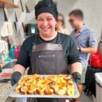 Ajudante de churrasqueiro com bandeja de pães de alho servindo convidados