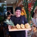 Auxiliar de churrasqueiro para festa servindo abacaxis grelhados numa bandeja