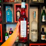 Mão segurando uma garrafa na vertical de xarope grenadine sabor romã Kally 700ml