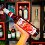 Mão segurando uma garrafa na diagonal de xarope grenadine sabor romã Kally 700ml