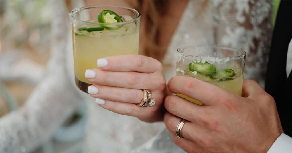 Noivos segurando copos de caipirinha durante um casamento