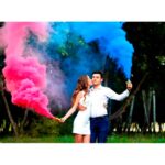 Casal soltando fumaça colorida rosa e azul.