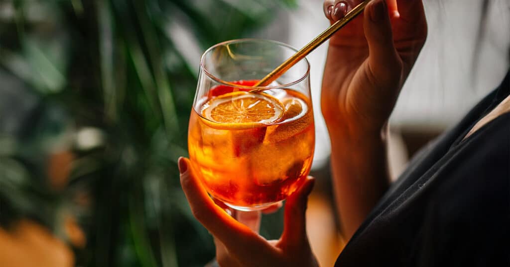 Mulher tomando o drink Aperol Spritz em uma festa
