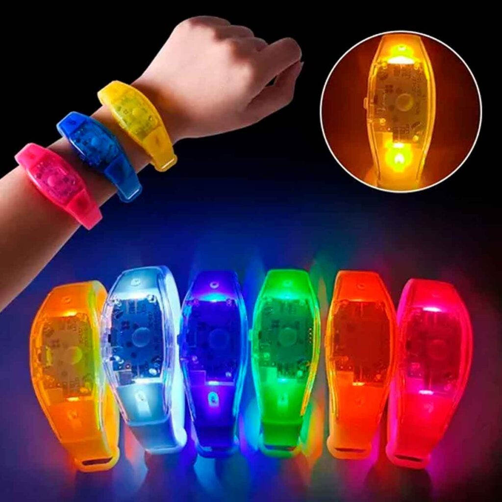 Braço com 3 pulseiras de LED ao lado superior esquerdo. No rodapé da imagem tem 6 pulseiras com o LED acesas em diferentes cores para exibir a luminância da pulseira de LED. Compre já!