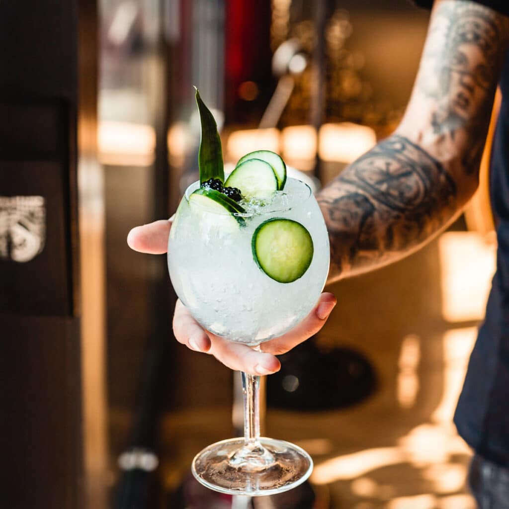 Bartender segurando um copo de Gin Tônica com especiarias em uma festa