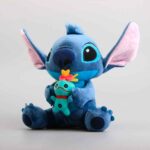 Pelúcia azul do personagem Stitch sentado e abraçando a boneca Scrump (Xepa).