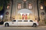 Limousine branca longa estacionada em frente a uma igreja iluminada à noite. Palavra-chave: limousine para casamento em São Paulo.