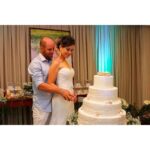 Filmagem de casamento em Curitiba: Noivos cortando o bolo da festa com alegria.