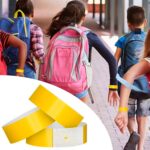 Pulseira de identificação amarela em crianças com mochilas, ideal para passeios escolares.