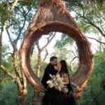 Casal se beijando em cenário de casamento ao ar livre no campo, com estilo rústico e romântico